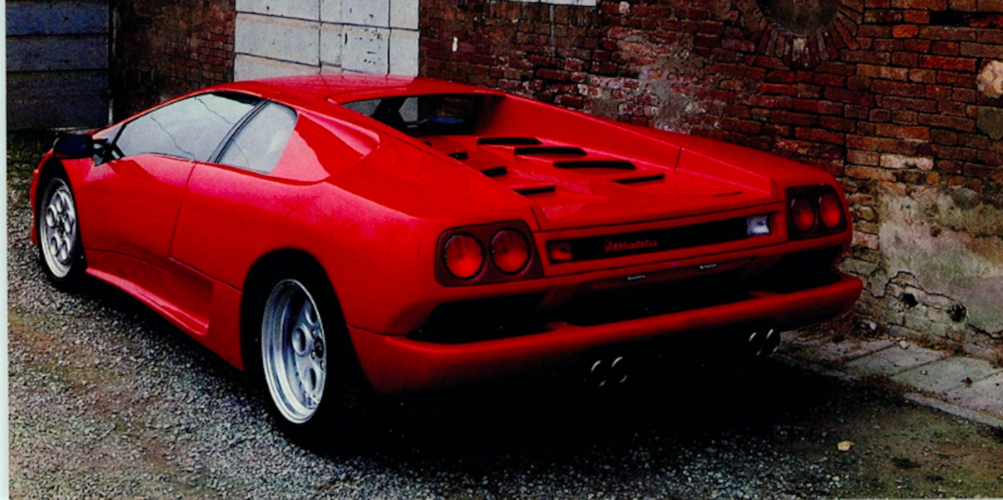 Une Lamborghini Diablo VT jaune de 1990, portes en ciseaux légèrement ouvertes, sur une route moderne.