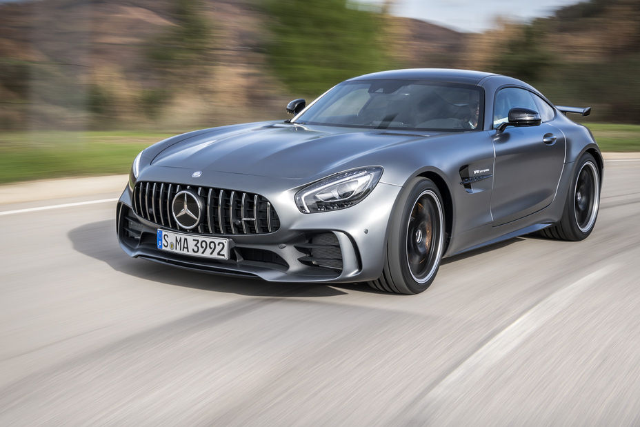 Vue rapprochée d'une Mercedes-AMG GT-R rouge vif sur une piste de course, mettant en valeur sa calandre agressive et ses phares élégants.