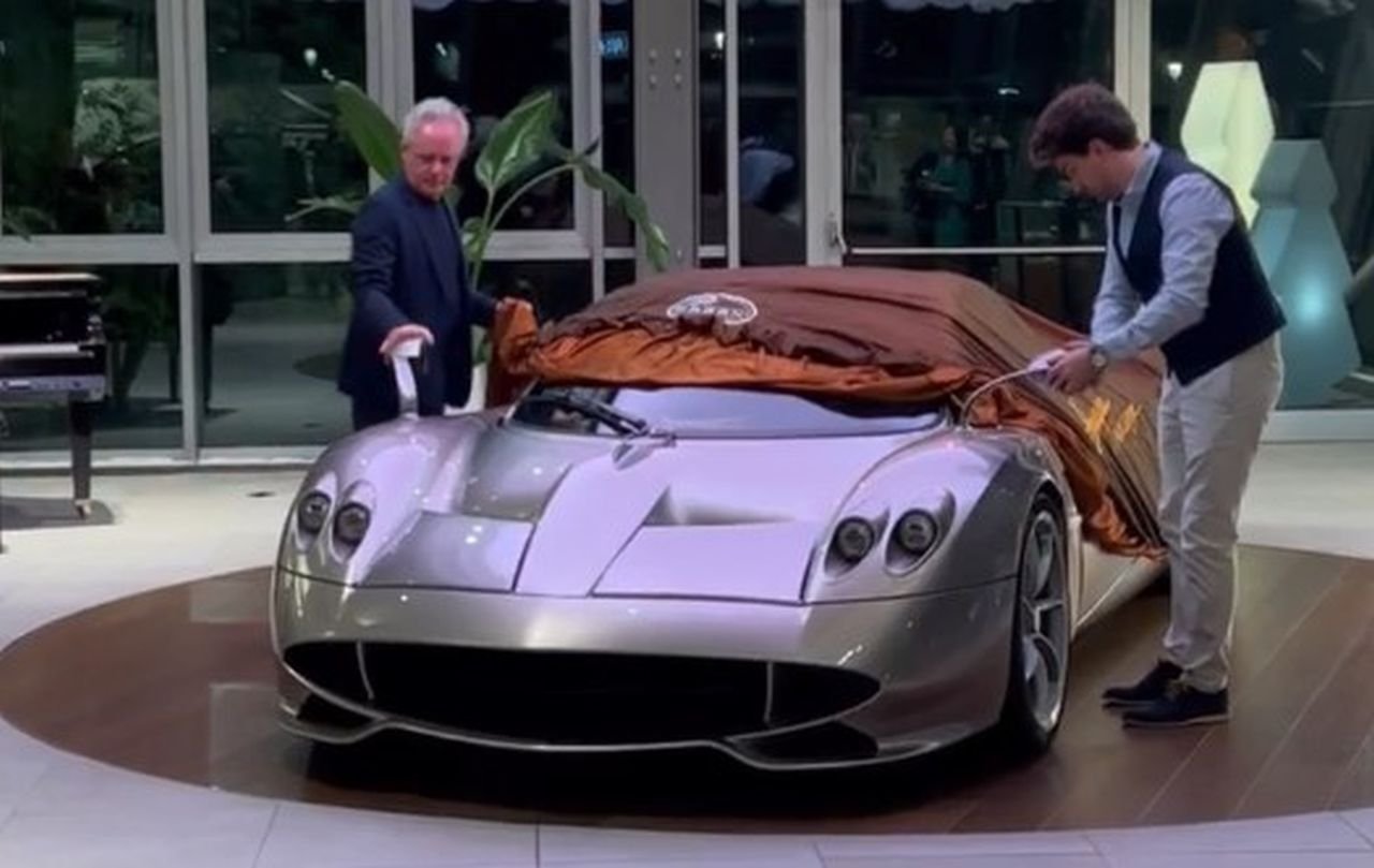 Une Pagani Huayra Codalunga bleu nuit avec des accents dorés, garée devant des gratte-ciel et des yachts à Dubaï.