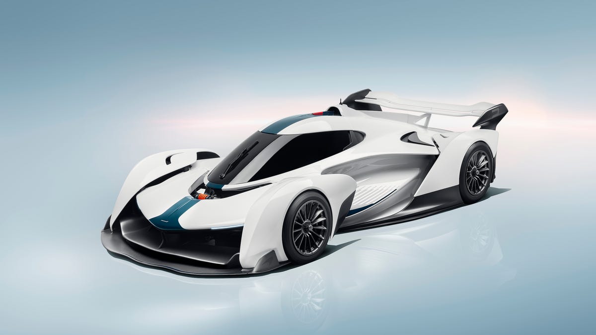 Vue latérale d'une McLaren Solus GT-R noire et orange, garée sur une piste de course.