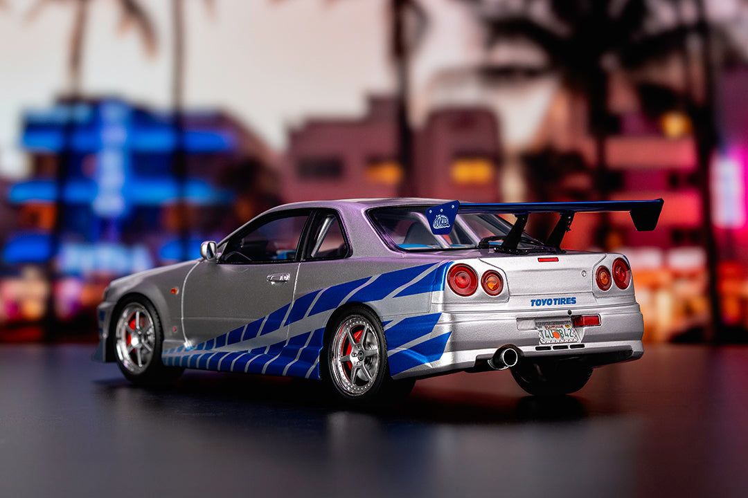 Une vue rapprochée de l'arrière d'une Nissan Skyline GT-R R34, mettant en évidence ses feux ronds et son grand aileron arrière.