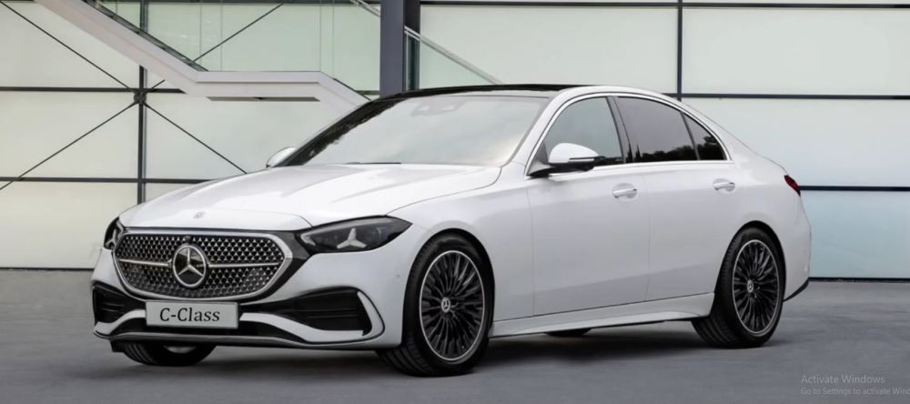 Vue avant d'une Mercedes-Benz Classe C (W206) restylée, présentant des phares et une calandre modernisés, garée dans une rue urbaine au crépuscule.