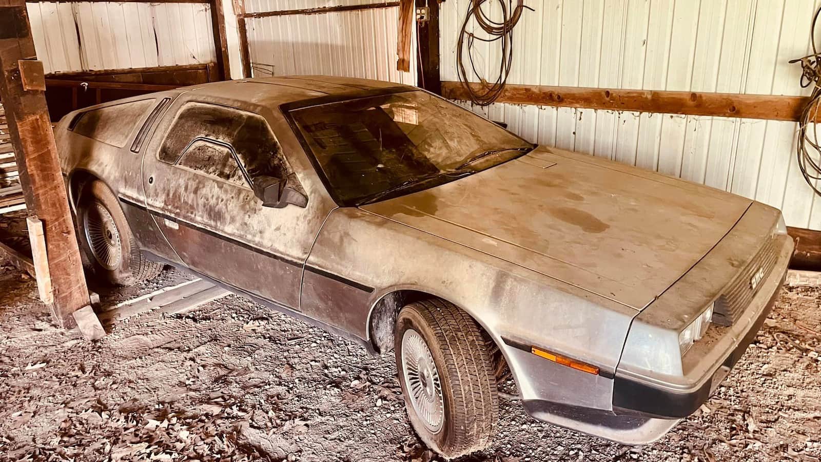 Une DeLorean DMC-12 poussiéreuse et bâchée dans un garage sombre, symbolisant une découverte inattendue.