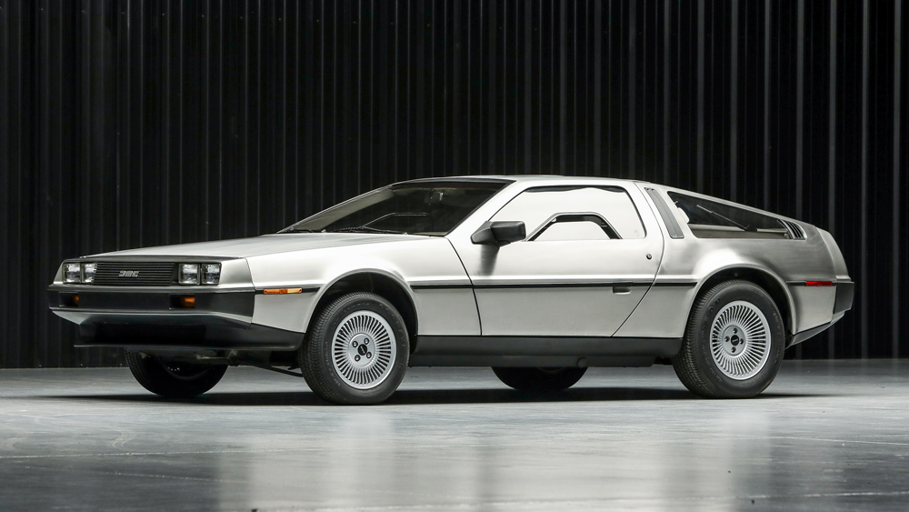 Une DeLorean DMC-12 immaculée avec des documents d'usine et des manuels d'entretien étalés, soulignant son état exceptionnel.
