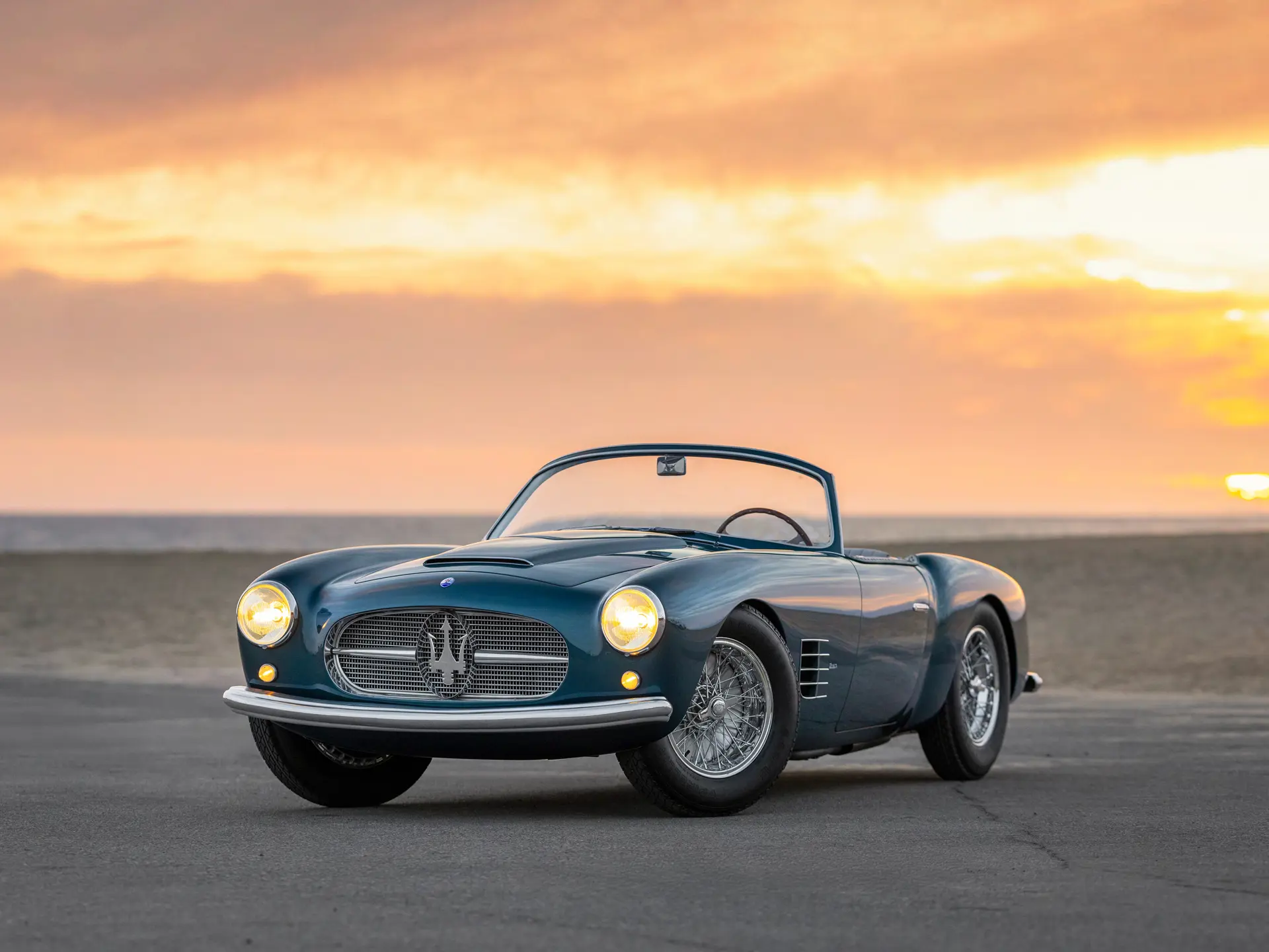 Vue latérale d'une Maserati A6G/54 Spyder Zagato rouge, garée devant une villa italienne, mettant en valeur son design élégant et ses courbes distinctives.