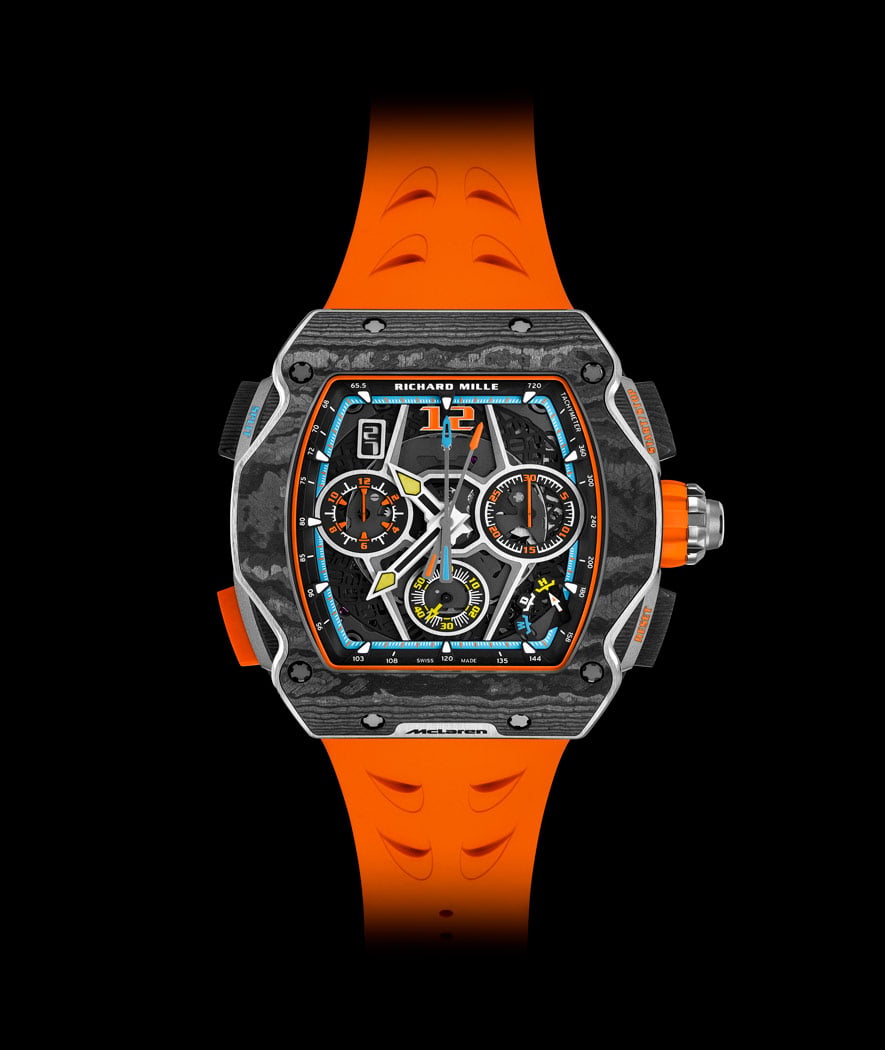 Une montre de luxe avec des éléments de design McLaren, posée sur une surface sombre et réfléchissante.