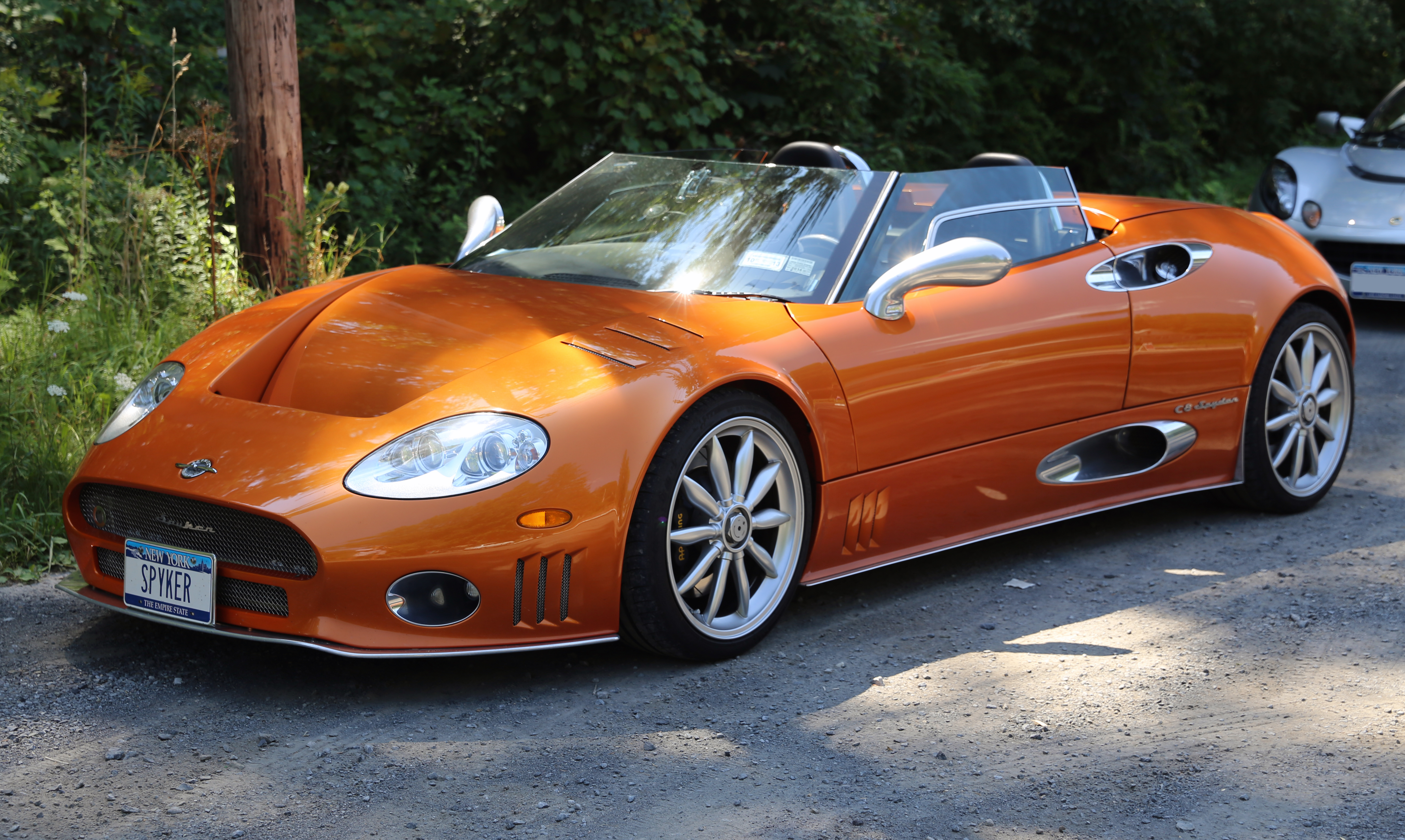 Une Spyker C8 Laviolette de couleur argent, vue de trois quarts avant, garée dans un garage moderne et épuré.
