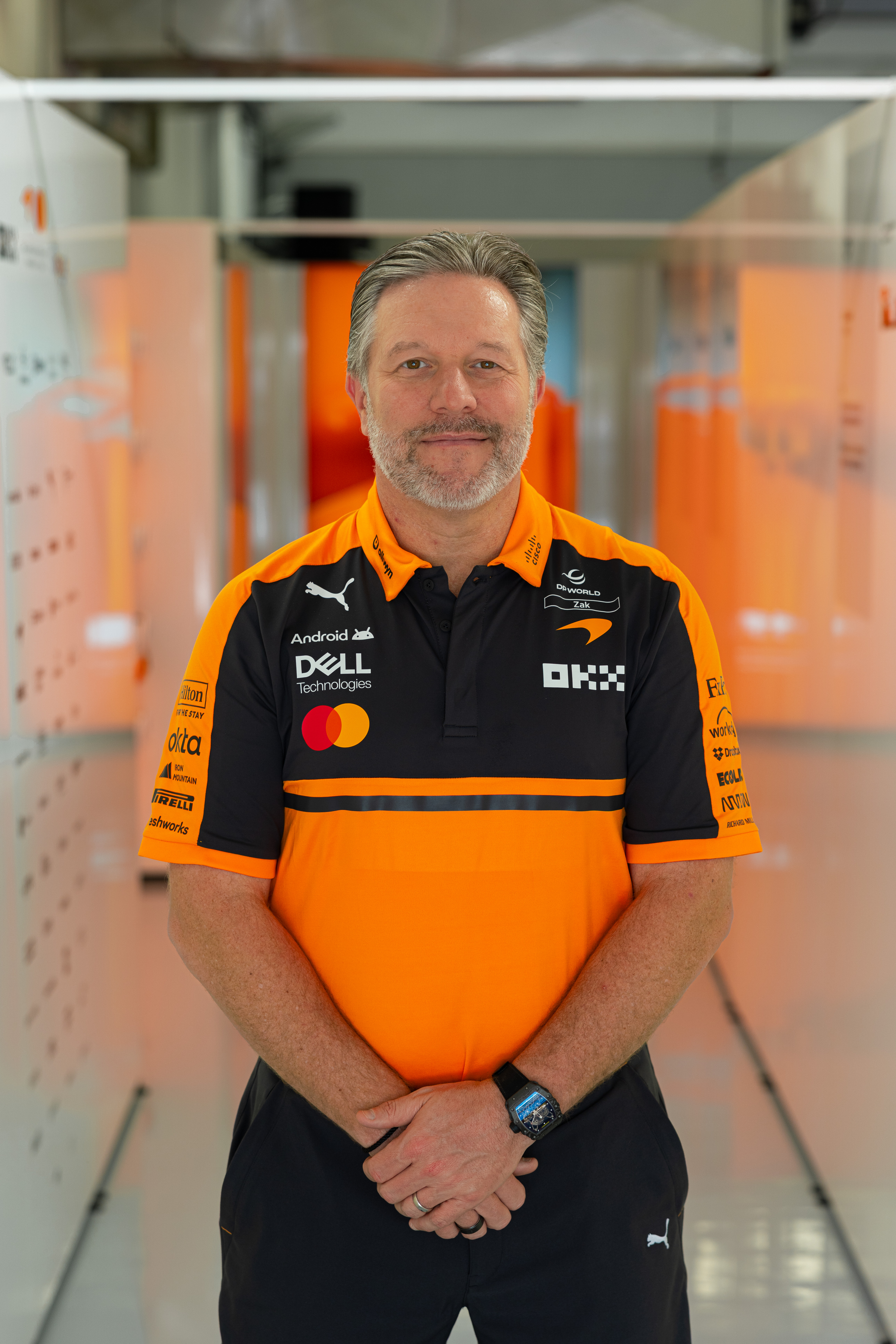 Zak Brown, directeur général de McLaren, dans le paddock de la Formule 1, l'air déterminé, entouré de l'agitation d'un week-end de course.