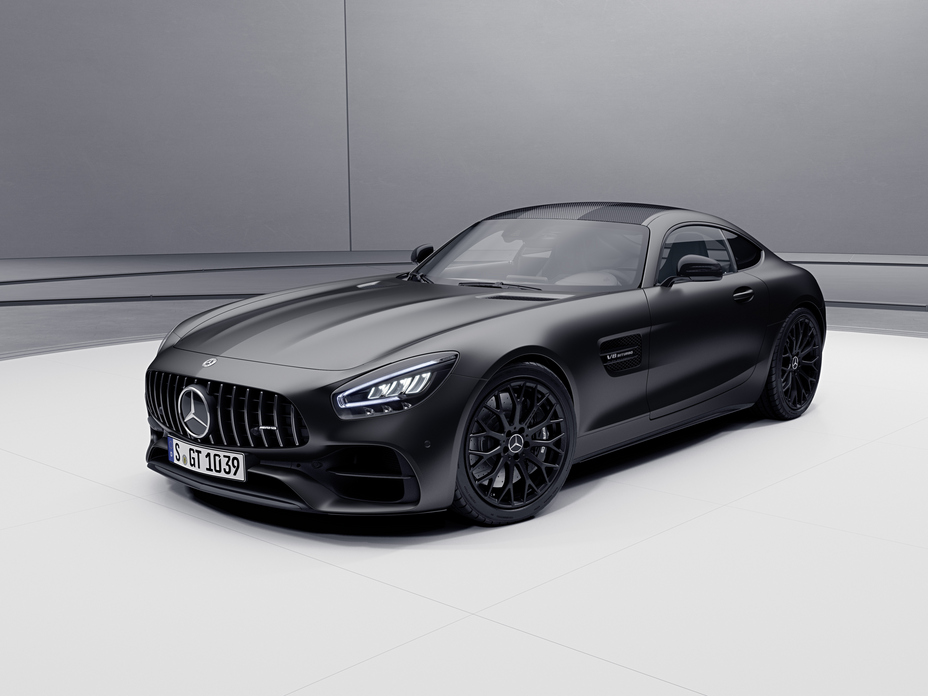 Une Mercedes-AMG GT noire en pleine accélération sur une piste de course, avec un flou de mouvement suggérant la vitesse.