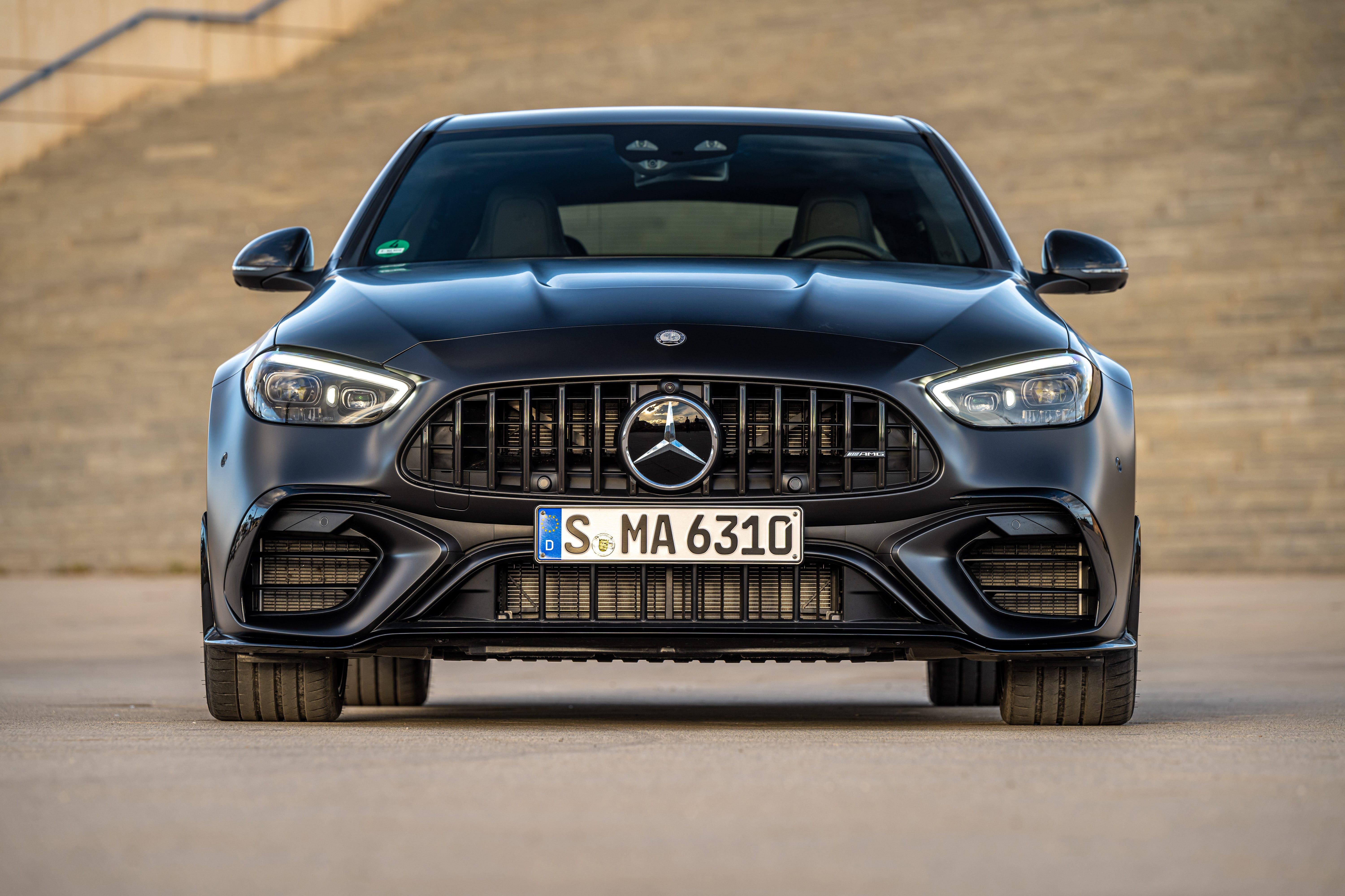 Vue avant dynamique de la Mercedes-AMG C 63 E PERFORMANCE, mettant en valeur sa calandre distinctive et ses lignes sportives.