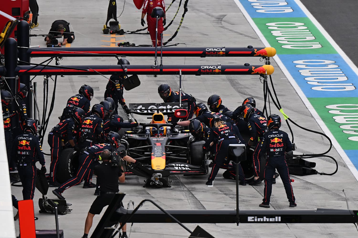 Une équipe de Formule 1 en plein travail dans les stands, utilisant des outils technologiques avancés.