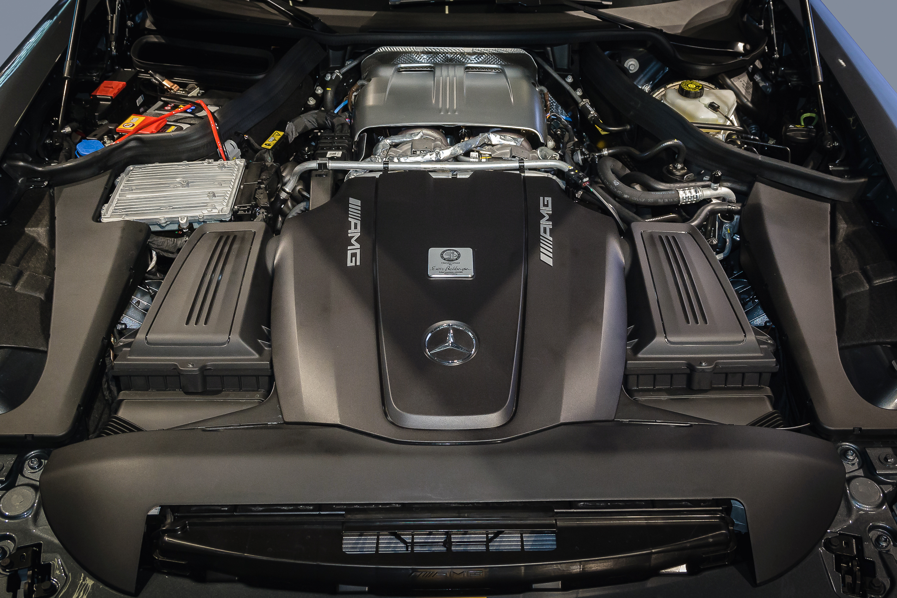Un gros plan détaillé sur un moteur Mercedes-AMG V8 biturbo, avec ses éléments en fibre de carbone et ses surfaces métalliques brillantes.