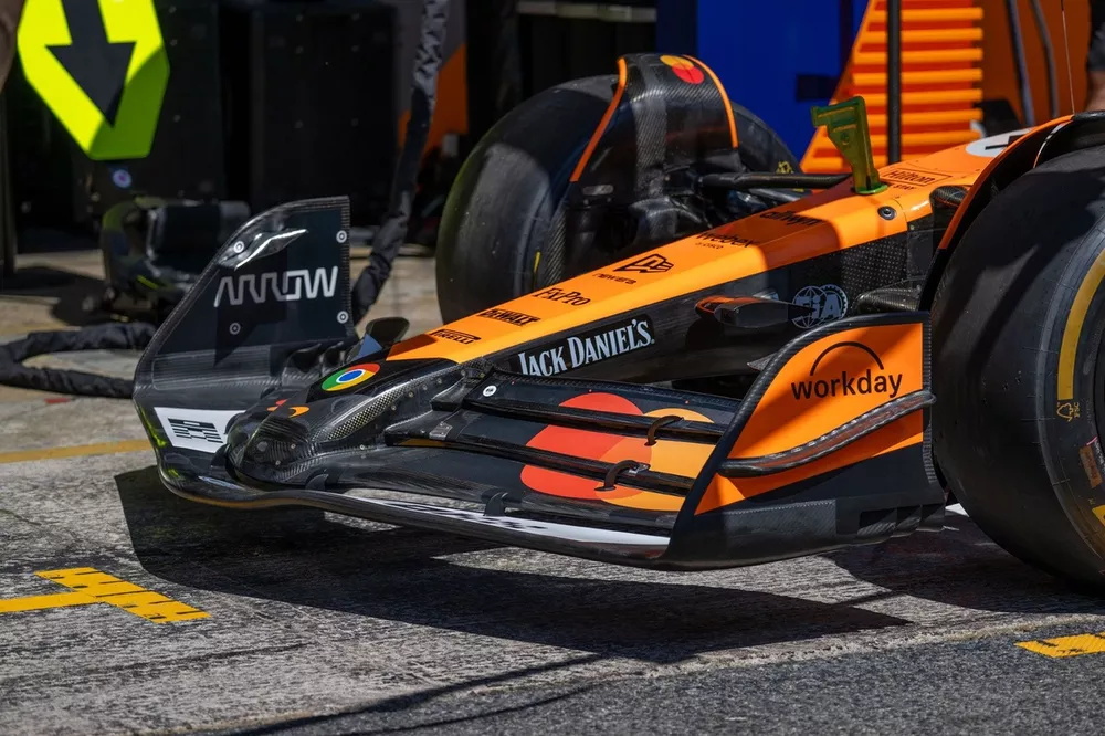 Une voiture de Formule 1 McLaren en action sur la piste, mettant en évidence les nouvelles pièces aérodynamiques telles que le fond plat et le châssis modifiés.