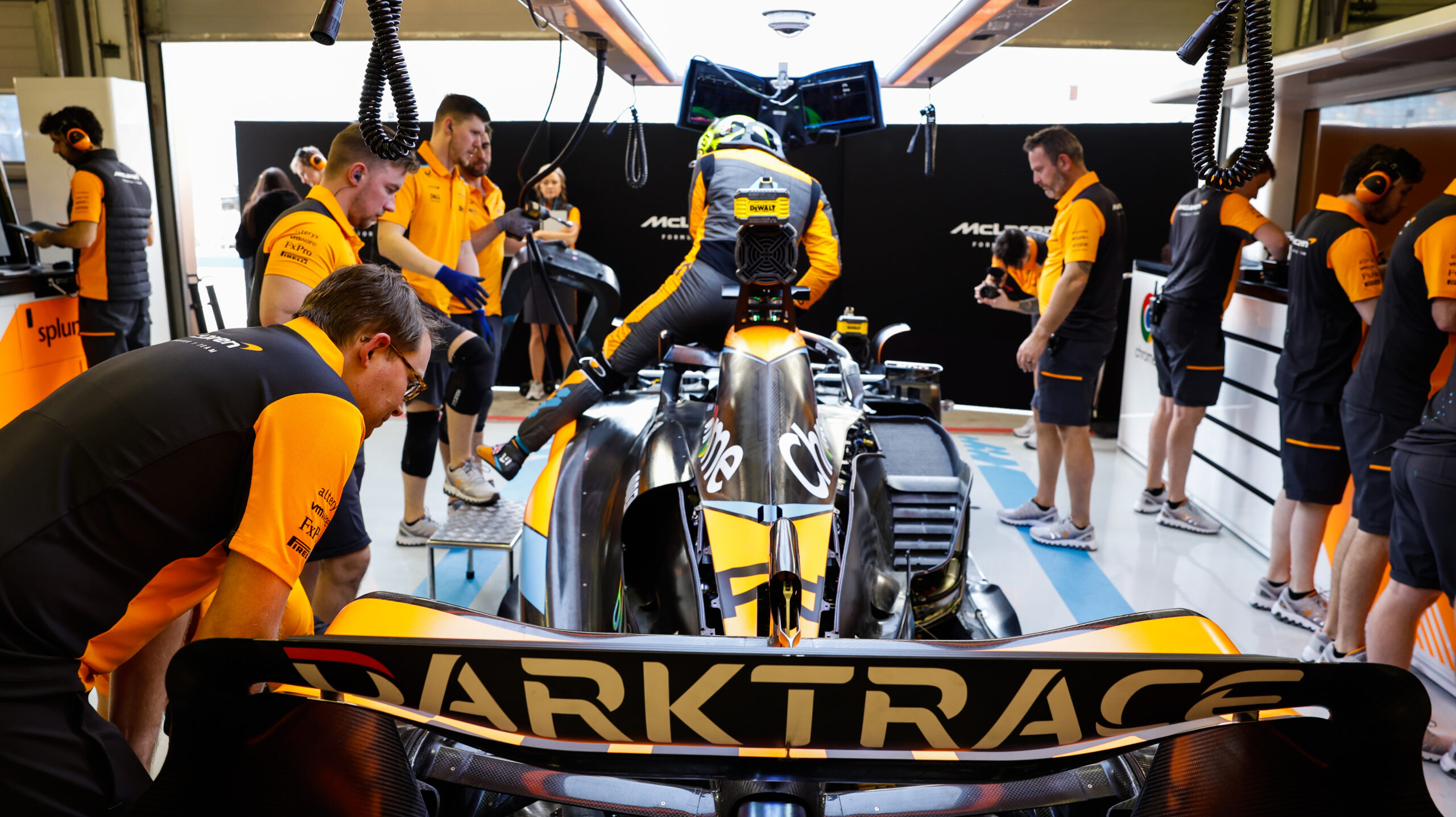 Des stratèges de l'équipe McLaren de Formule 1 dans une salle de contrôle de course, surveillant des écrans de données.