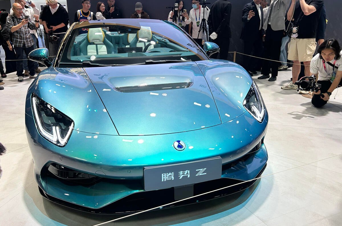 Une supercar électrique Denza Z de couleur vive, filant à toute vitesse sur une piste d'essai, avec un arrière-plan flou pour accentuer l'impression de mouvement.