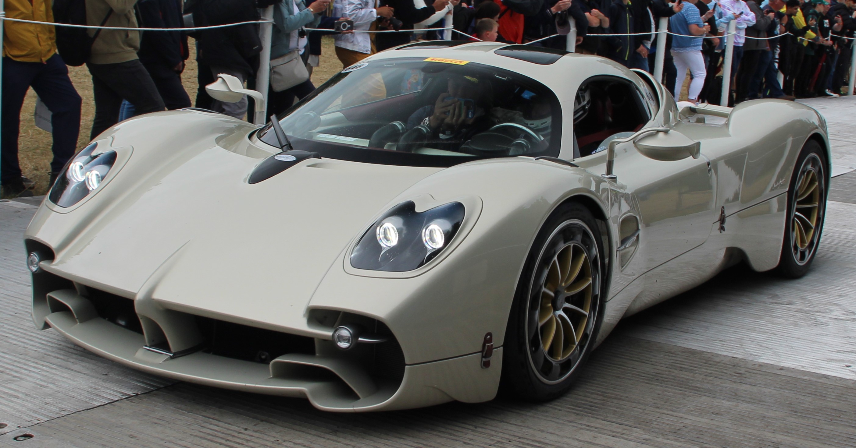 Une Pagani Utopia argentée, aux lignes épurées, exposée dans un showroom moderne avec un éclairage doux.