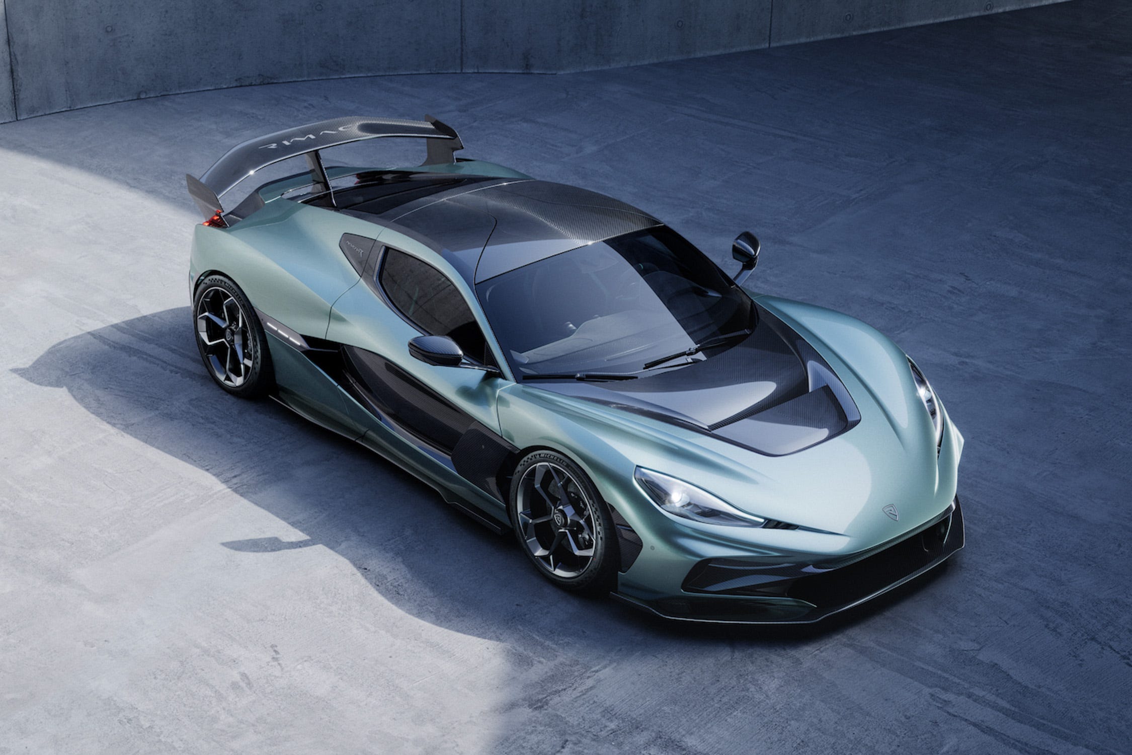 Vue latérale d'une Rimac Nevera R blanche et noire sur un circuit, mettant en évidence ses éléments aérodynamiques de course.
