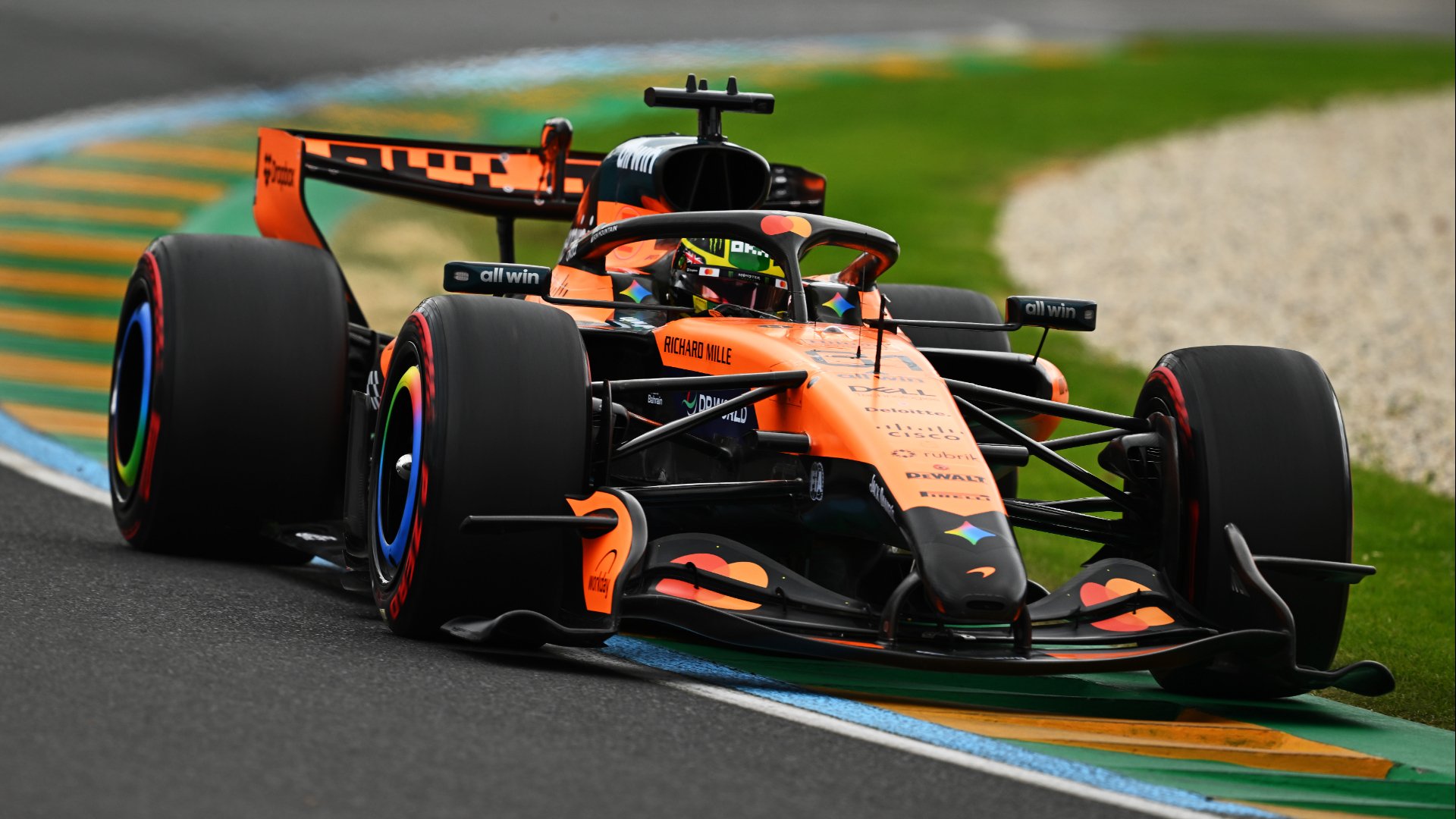 Une voiture de Formule 1 McLaren orange et noire en pleine course, avec le logo Mercedes-AMG visible sur le capot moteur.