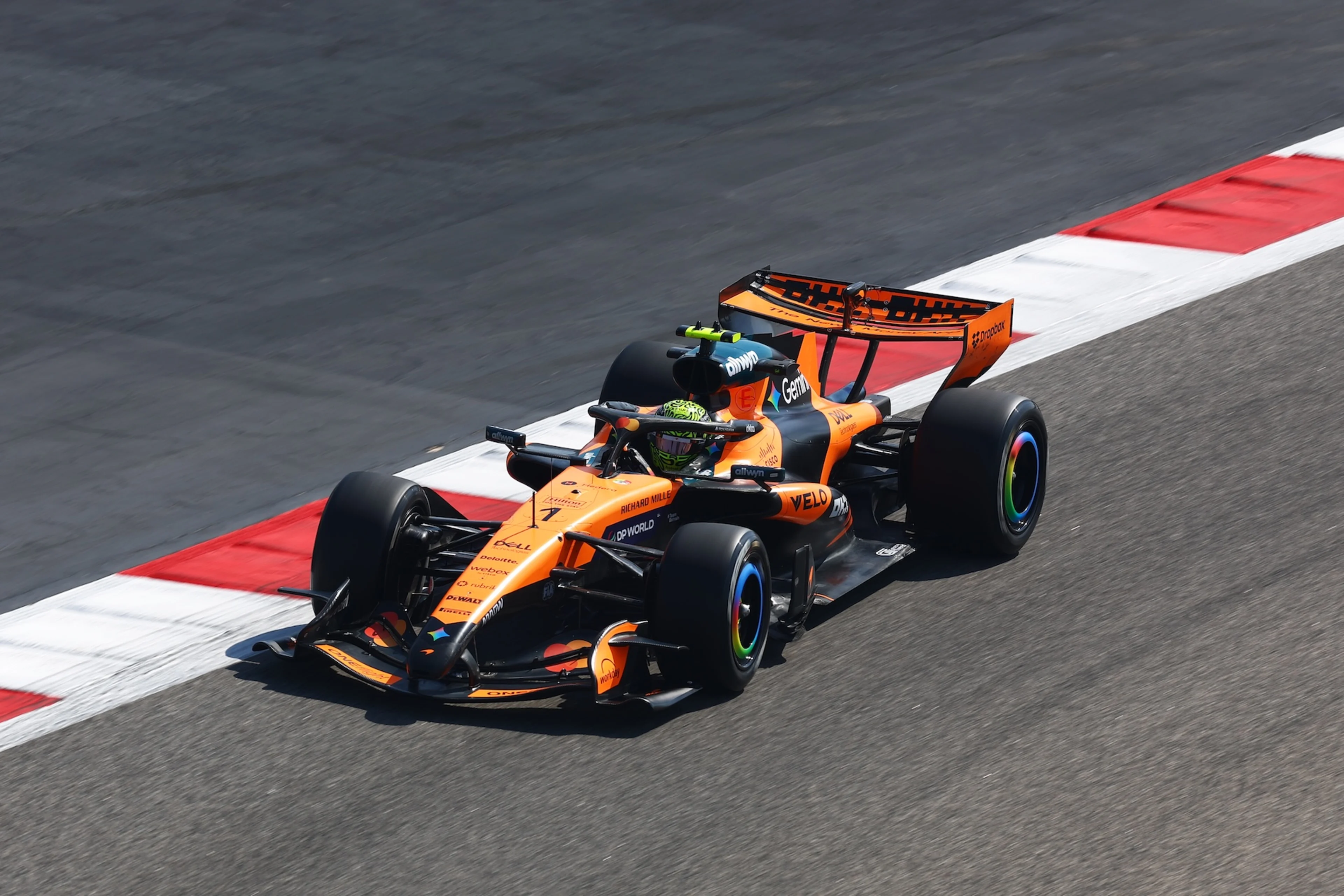 Une voiture de Formule 1 McLaren en mouvement sur un circuit, équipée de capteurs pour l'analyse aérodynamique.