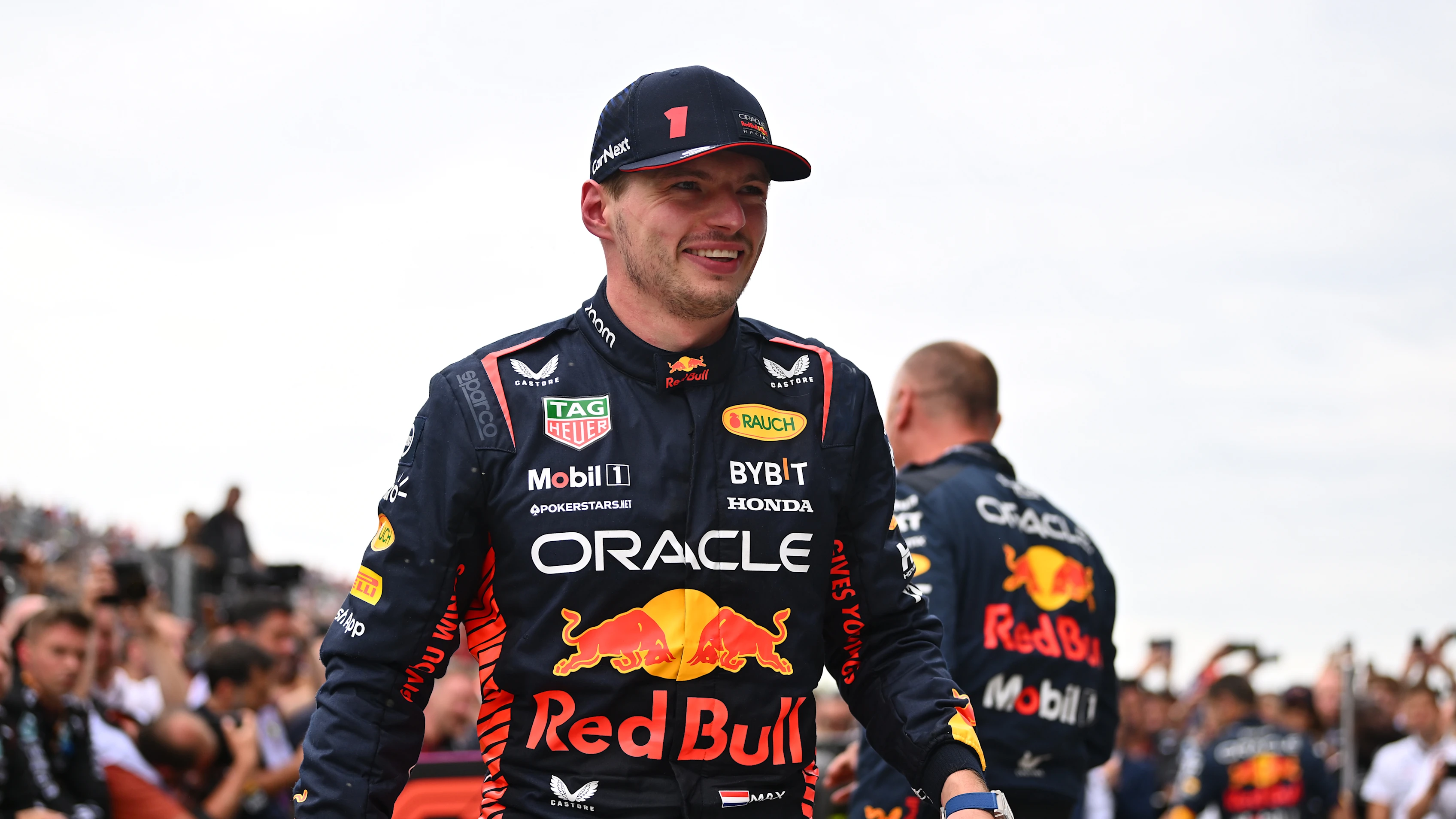 Max Verstappen en tenue de course Red Bull, posant à côté de sa monoplace sur la piste.