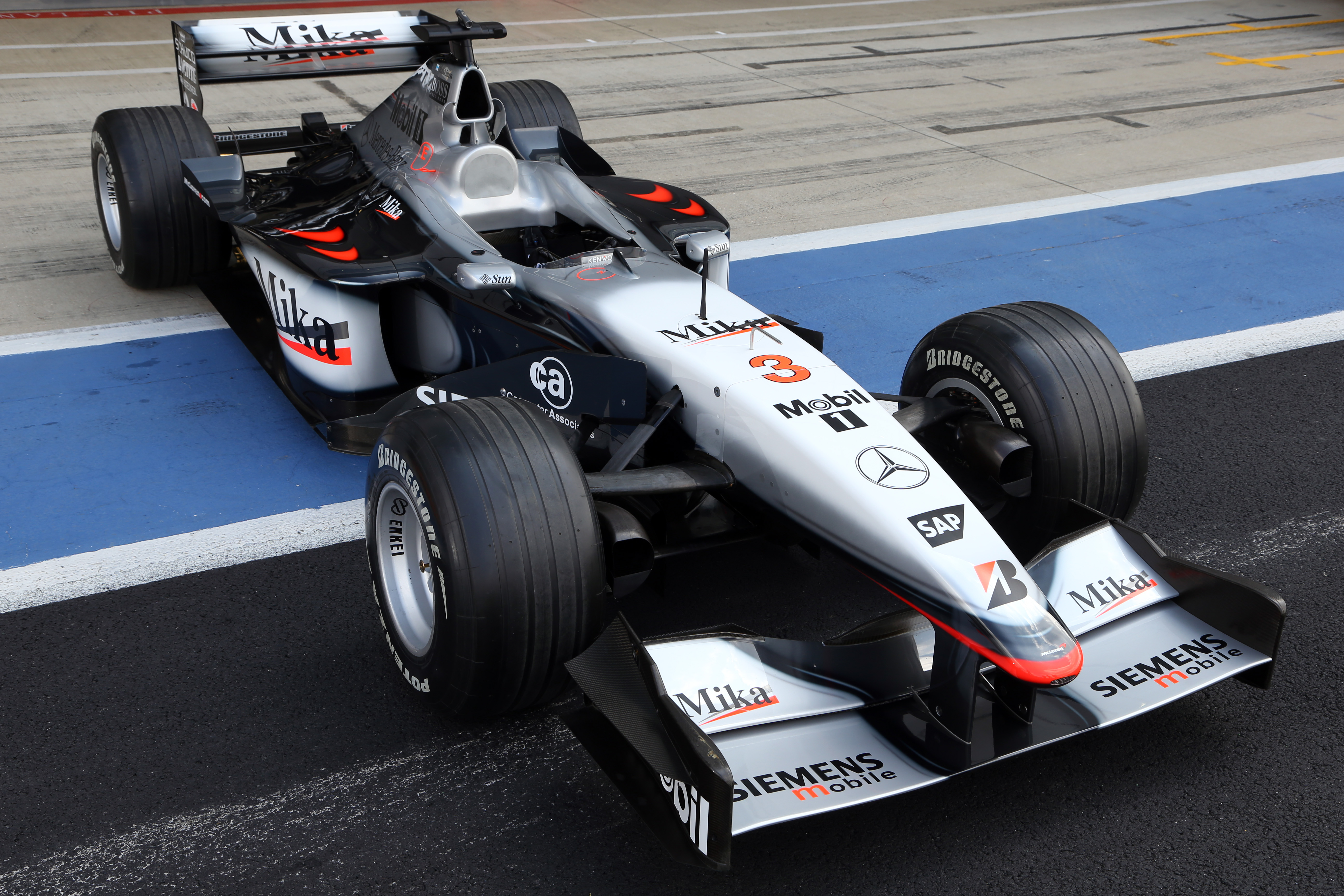 Une voiture de Formule 1 McLaren en pleine course, avec le moteur Mercedes visible, symbolisant le partenariat technique actuel.