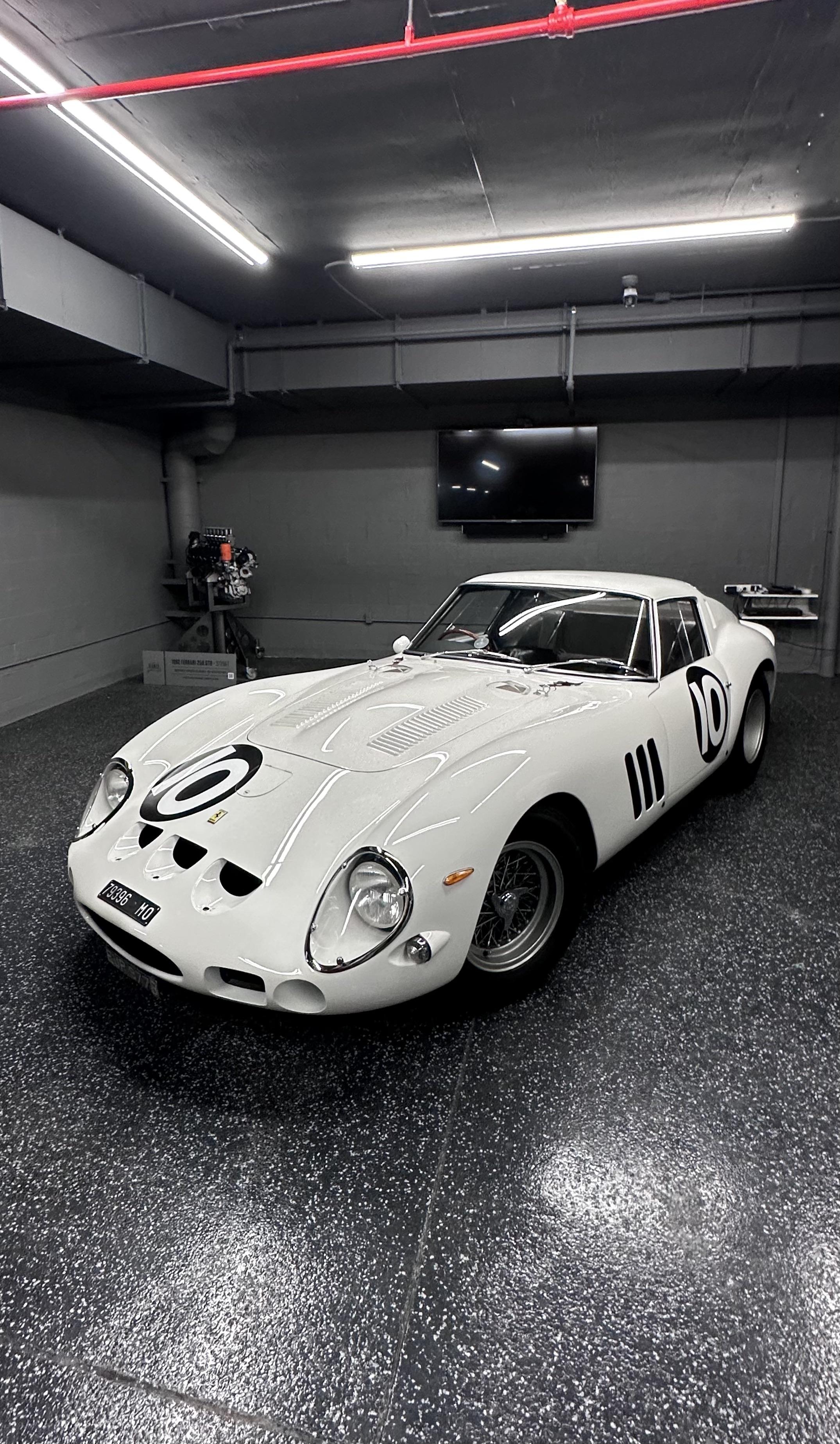 David SK Lee posant à côté de sa Ferrari 250 GTO rouge de 1962 dans un garage.
