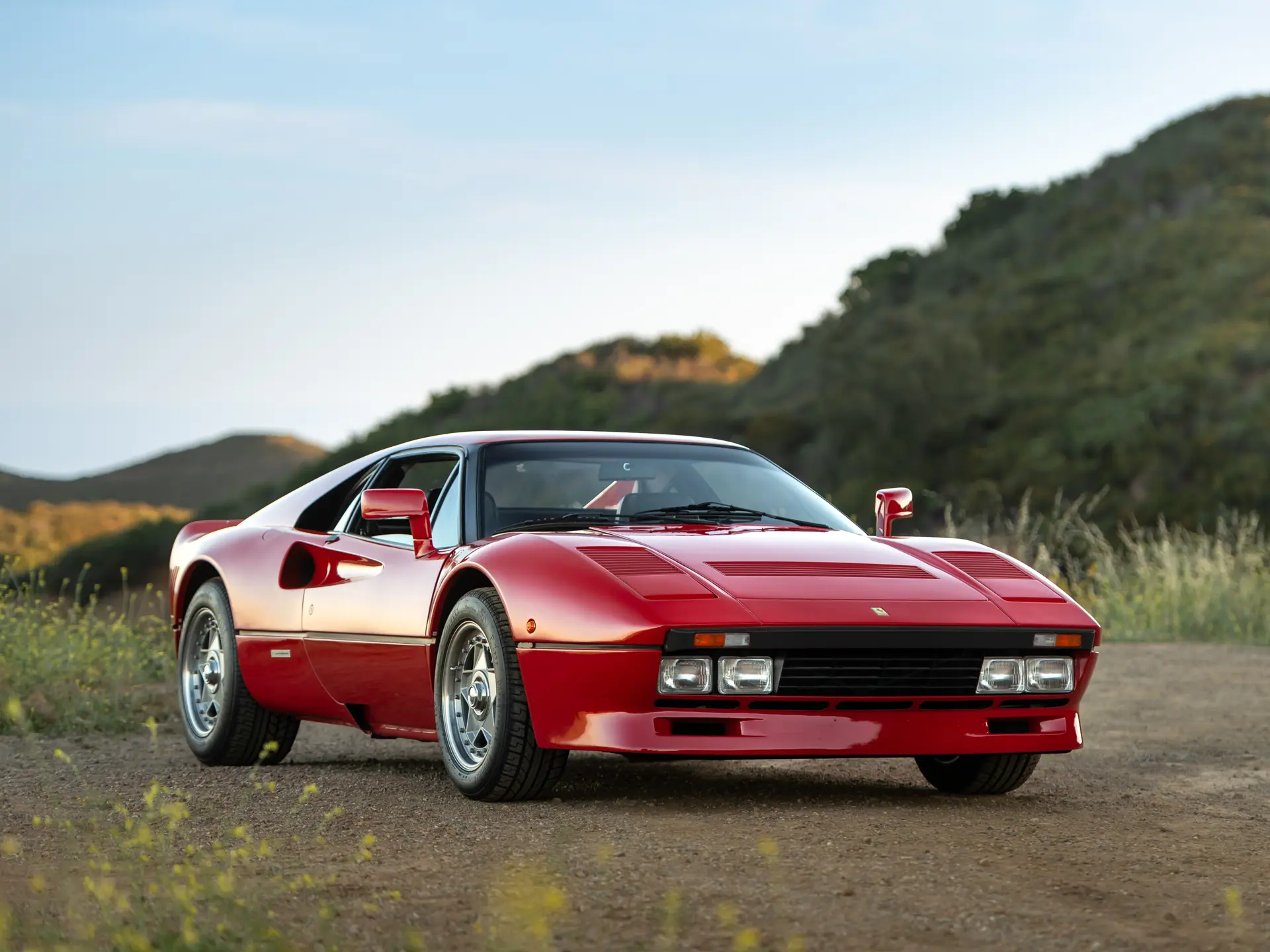 Une Ferrari 288 GTO rouge de 1985, garée dans un environnement élégant.