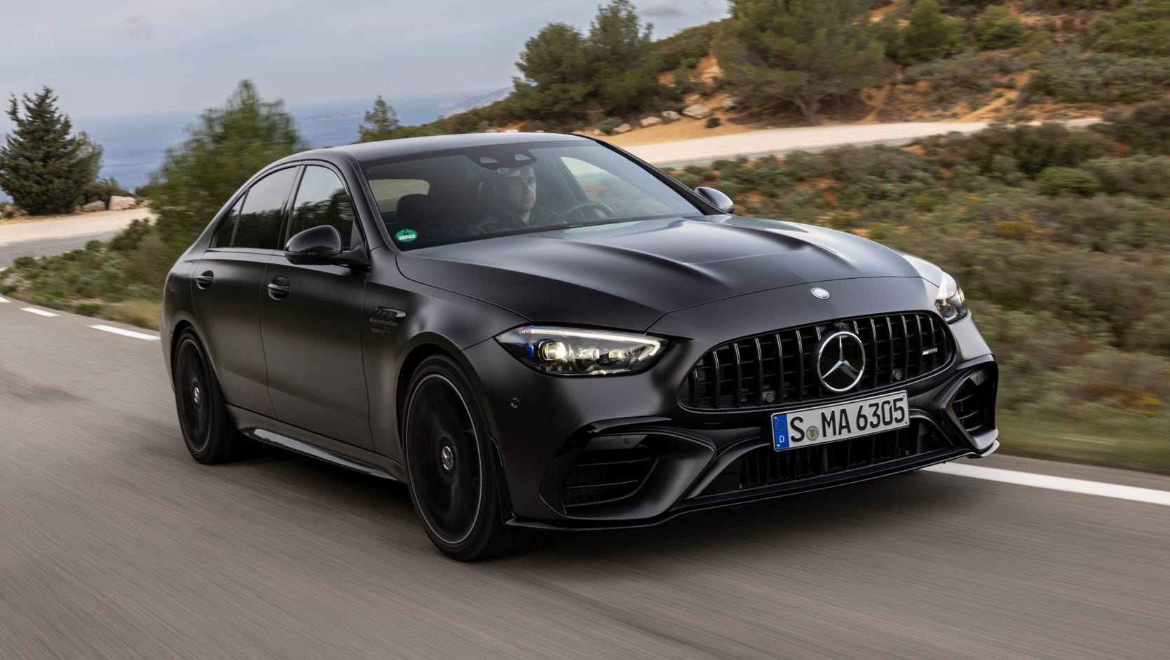 Une Mercedes-AMG C 63 S E Performance grise foncée en pleine accélération sur une piste de course, vue de côté et de près.