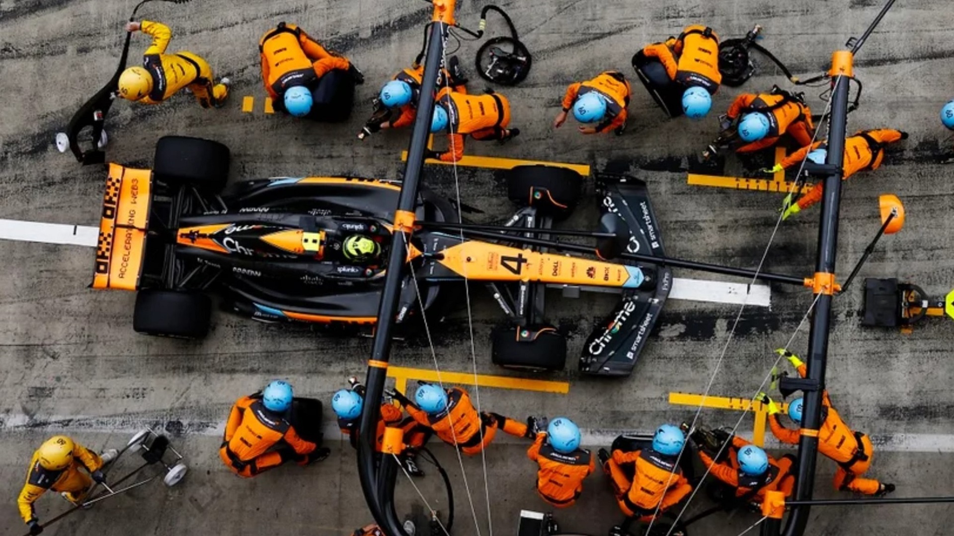 Équipe de McLaren effectuant un changement de pneus rapide d'intermédiaires à slicks lors d'un arrêt au stand.