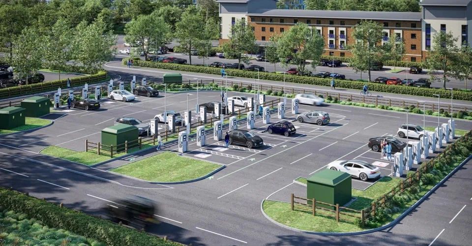 Une voiture électrique blanche est branchée à une borne de recharge dans une rue pavée d'une ville européenne.