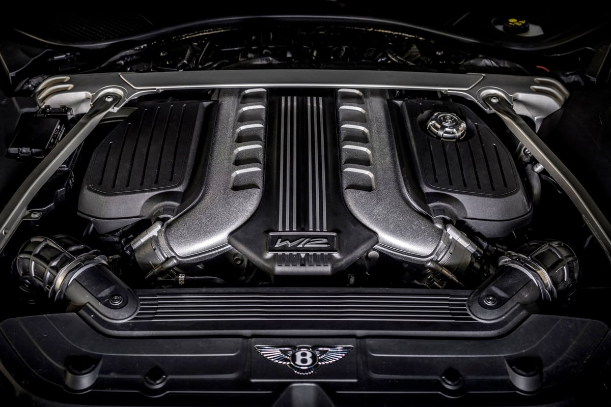 Gros plan sur un moteur Bentley W12, mettant en évidence ses composants complexes et sa finition luxueuse.