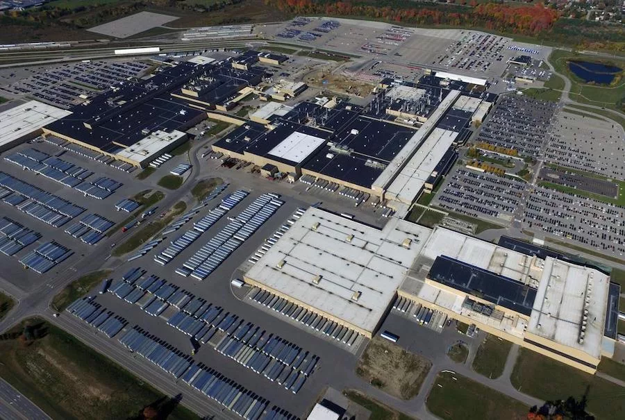 Une usine moderne et futuriste de véhicules électriques Honda, avec le logo Honda bien visible, située dans un paysage canadien.