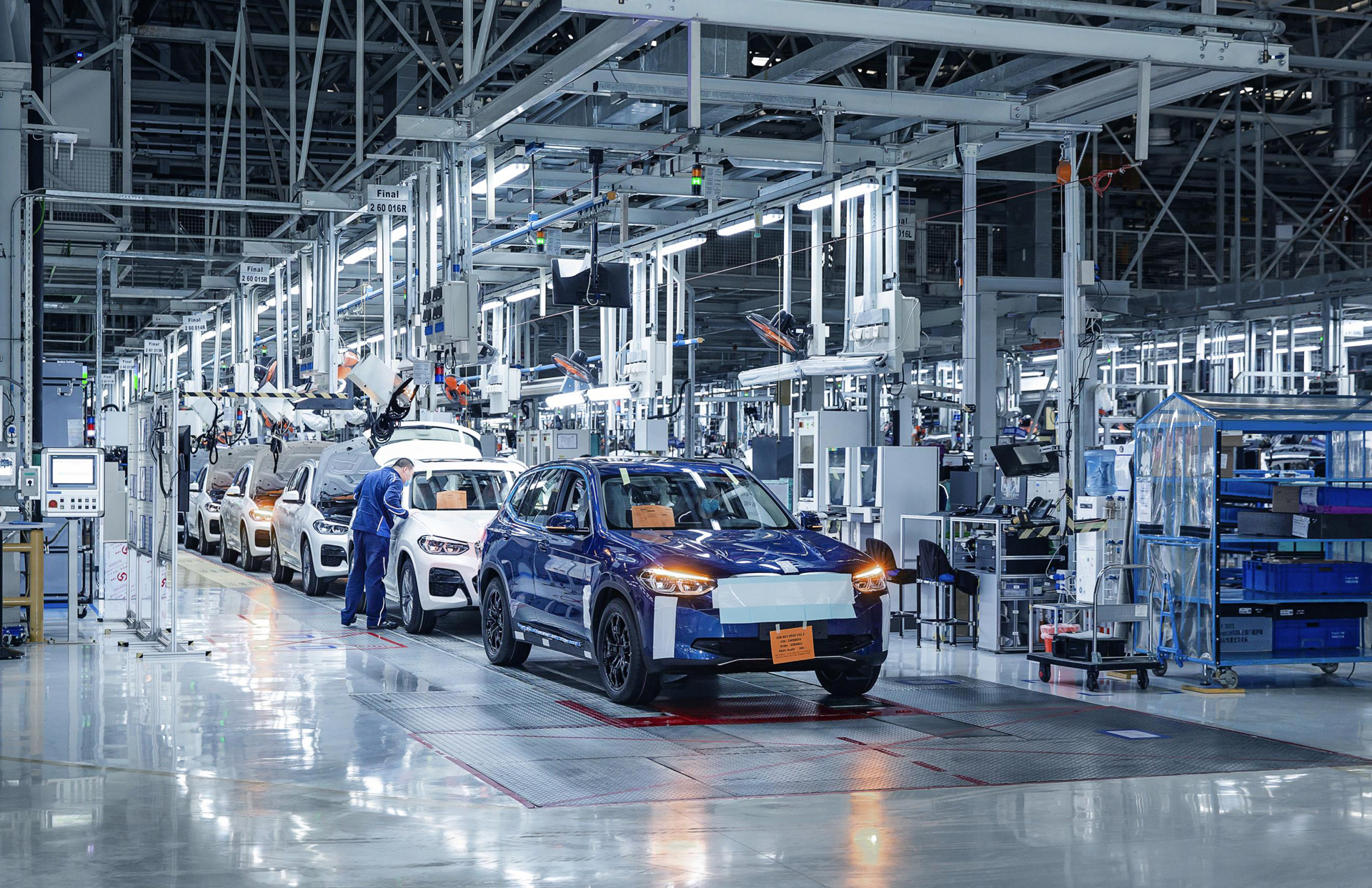 Vue d'une chaîne de montage moderne du BMW iX3 en Chine, avec des robots et des ouvriers assemblant le véhicule.