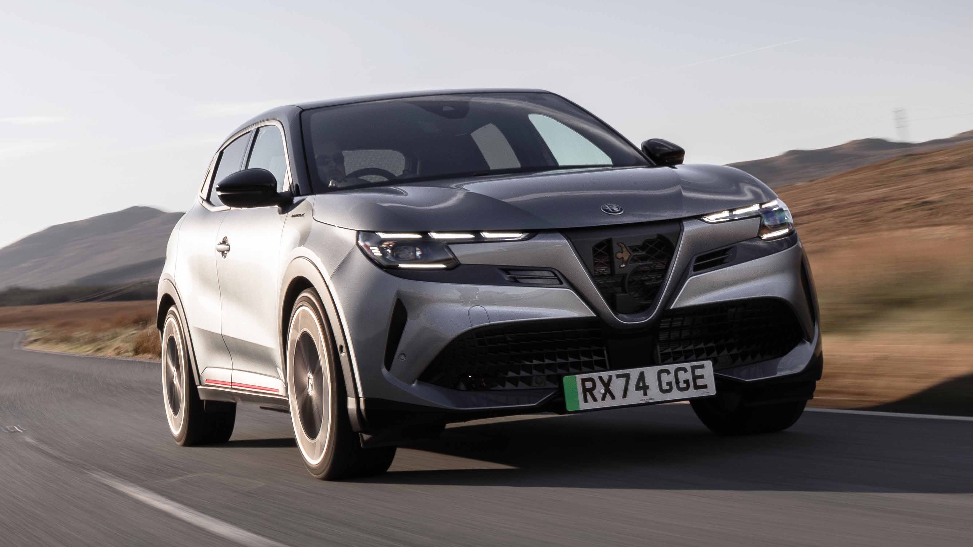 Une Alfa Romeo Junior électrique rouge est garée devant un bâtiment élégant, mettant en valeur son design sportif et raffiné.