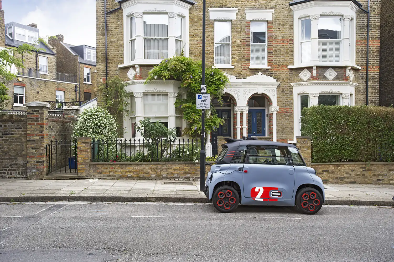 Une voiture électrique Citroën blanche est branchée à une borne de recharge publique dans un environnement urbain animé.