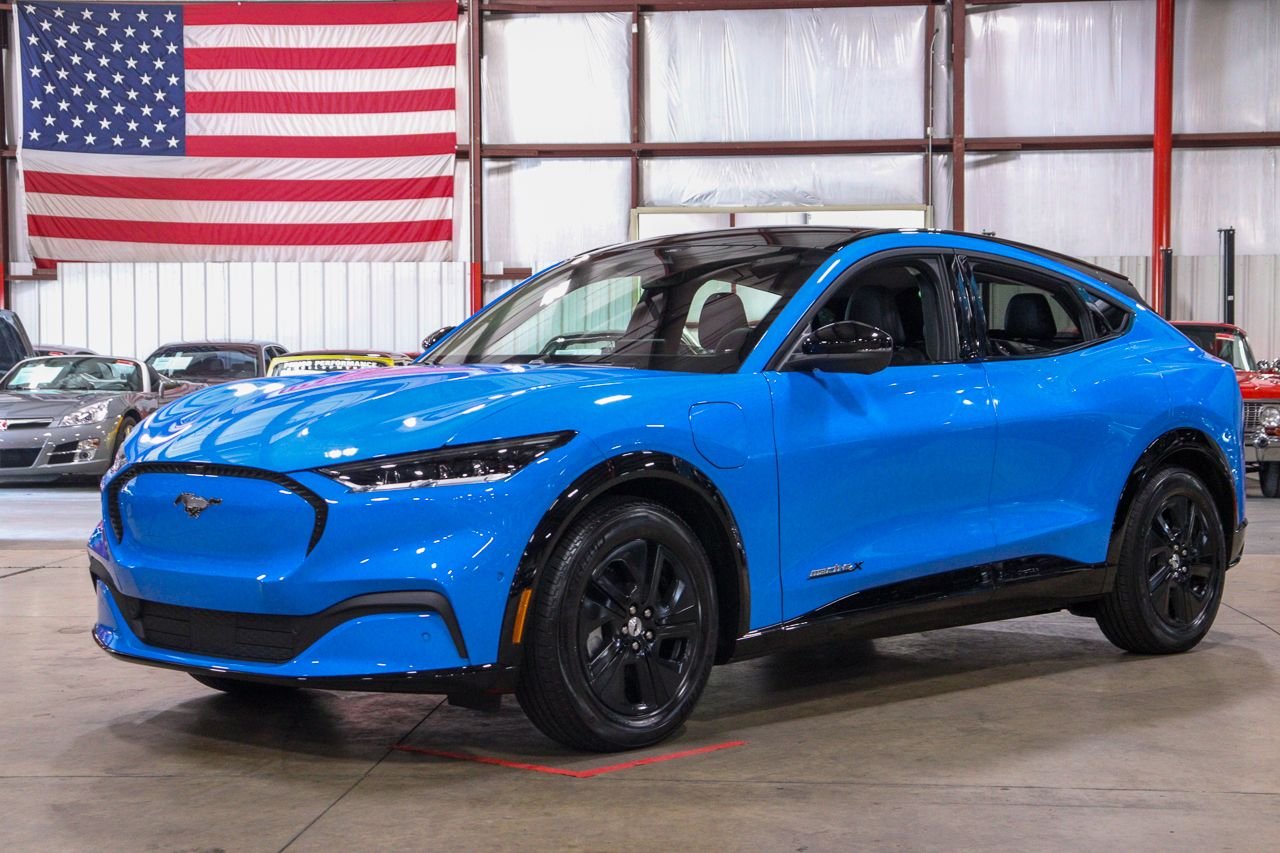 Une Ford Mustang Mach-E 2022 bleue foncée roule sur une route sinueuse en Californie, avec des montagnes en arrière-plan.