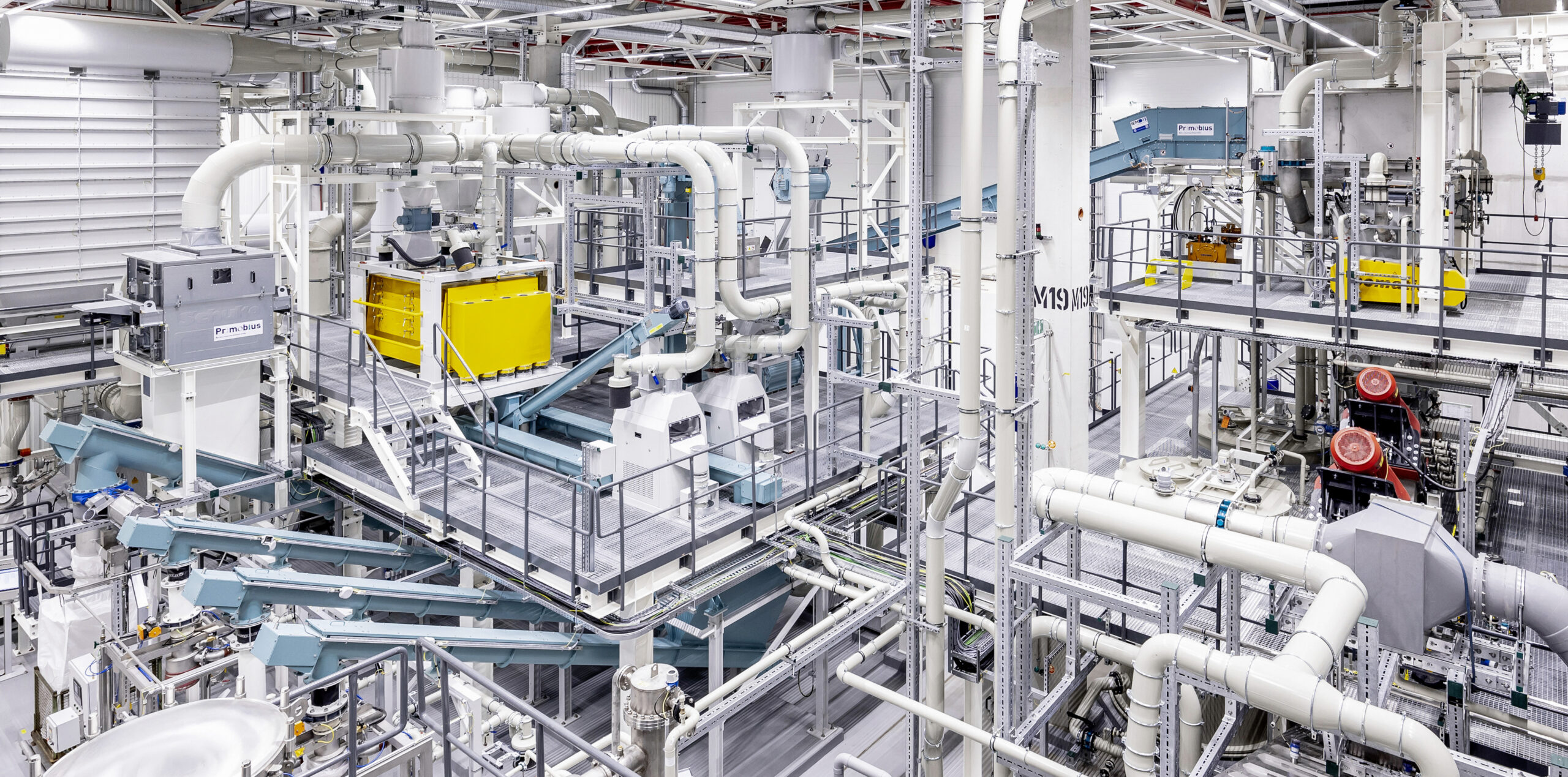 Photographie d'une usine de recyclage de batteries de véhicules électriques avec des machines modernes et des robots en action.