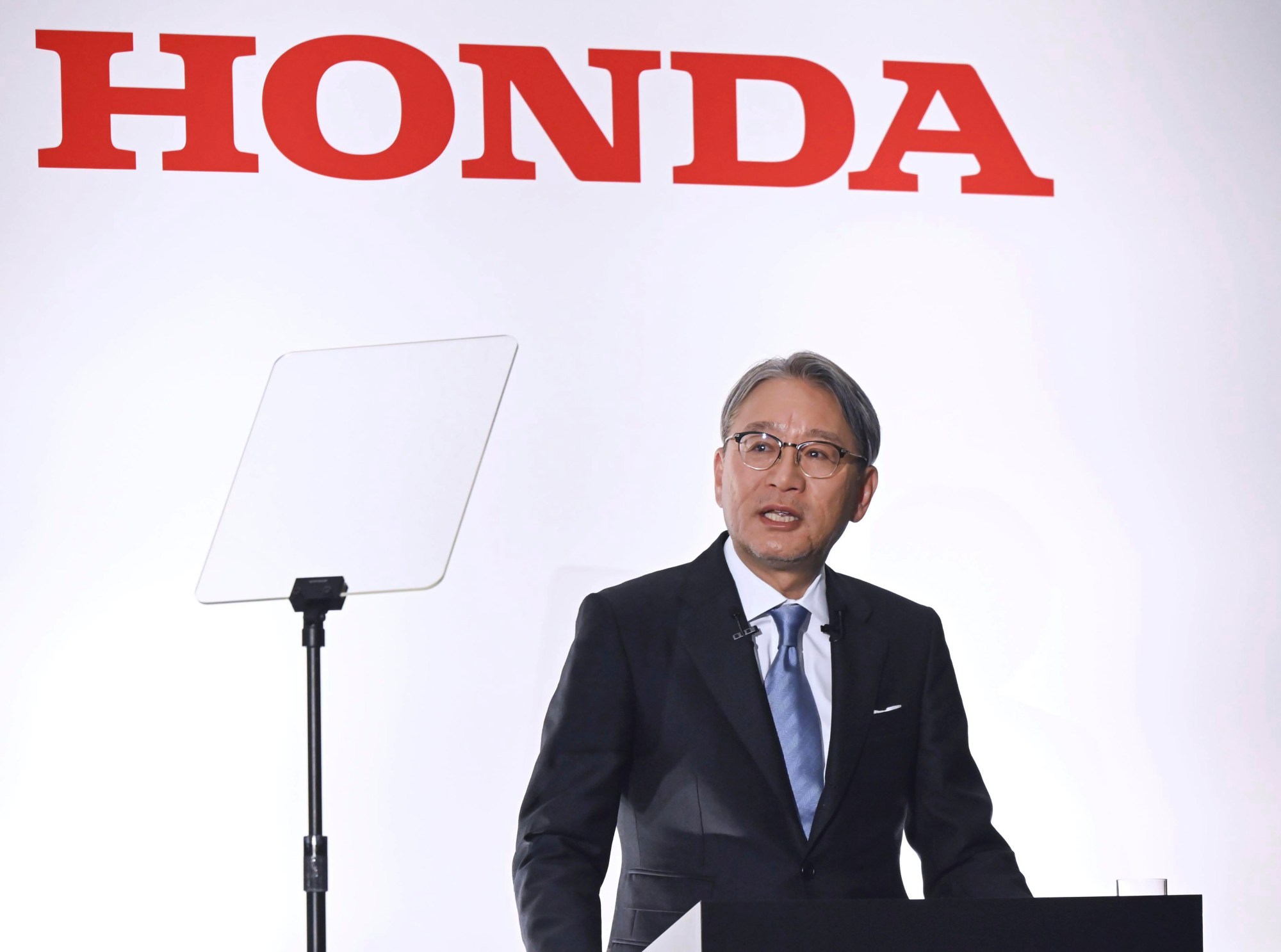 Des dirigeants de Honda en réunion, discutant de la stratégie des véhicules électriques avec des graphiques et des projections.