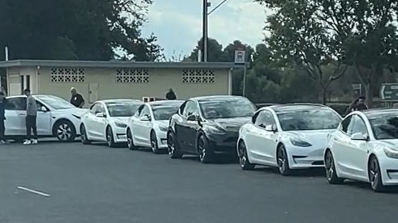 Une station de recharge pour voitures électriques très fréquentée avec une longue file de voitures en attente.