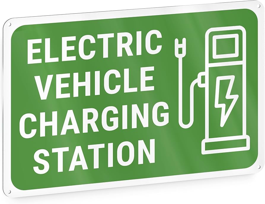 Une voiture électrique en train de charger à une borne de recharge avec une signalisation indiquant son usage exclusif.