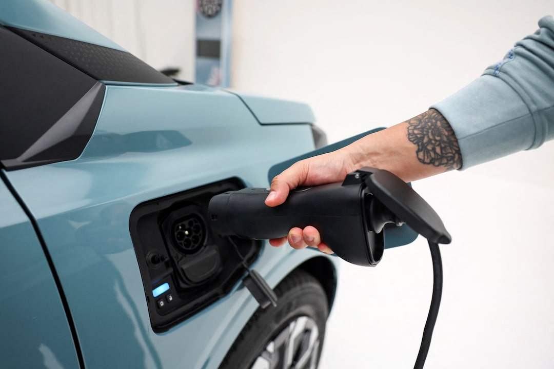 Une Dacia Spring bleue de 2026 en train de charger à une borne électrique moderne en ville, avec des bâtiments européens en arrière-plan.