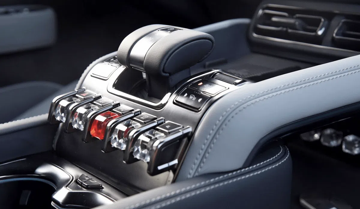 Une main appuyant sur un bouton physique sur le tableau de bord d'une voiture, illustrant la nouvelle réglementation chinoise.