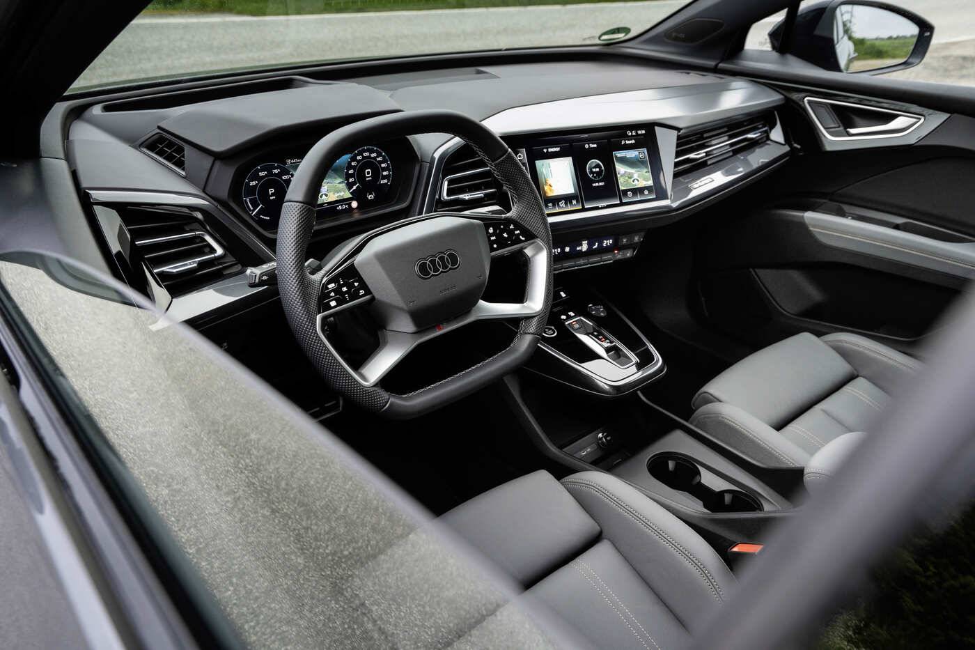 Vue de l'intérieur de l'Audi Q4 e-tron 2026, mettant en avant le tableau de bord numérique incurvé et l'écran central.