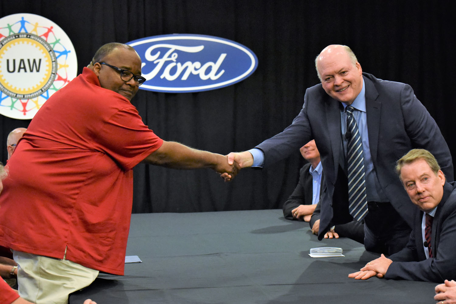 Deux dirigeants, l'un de Ford et l'autre de BYD, se serrant la main dans une salle de conférence.