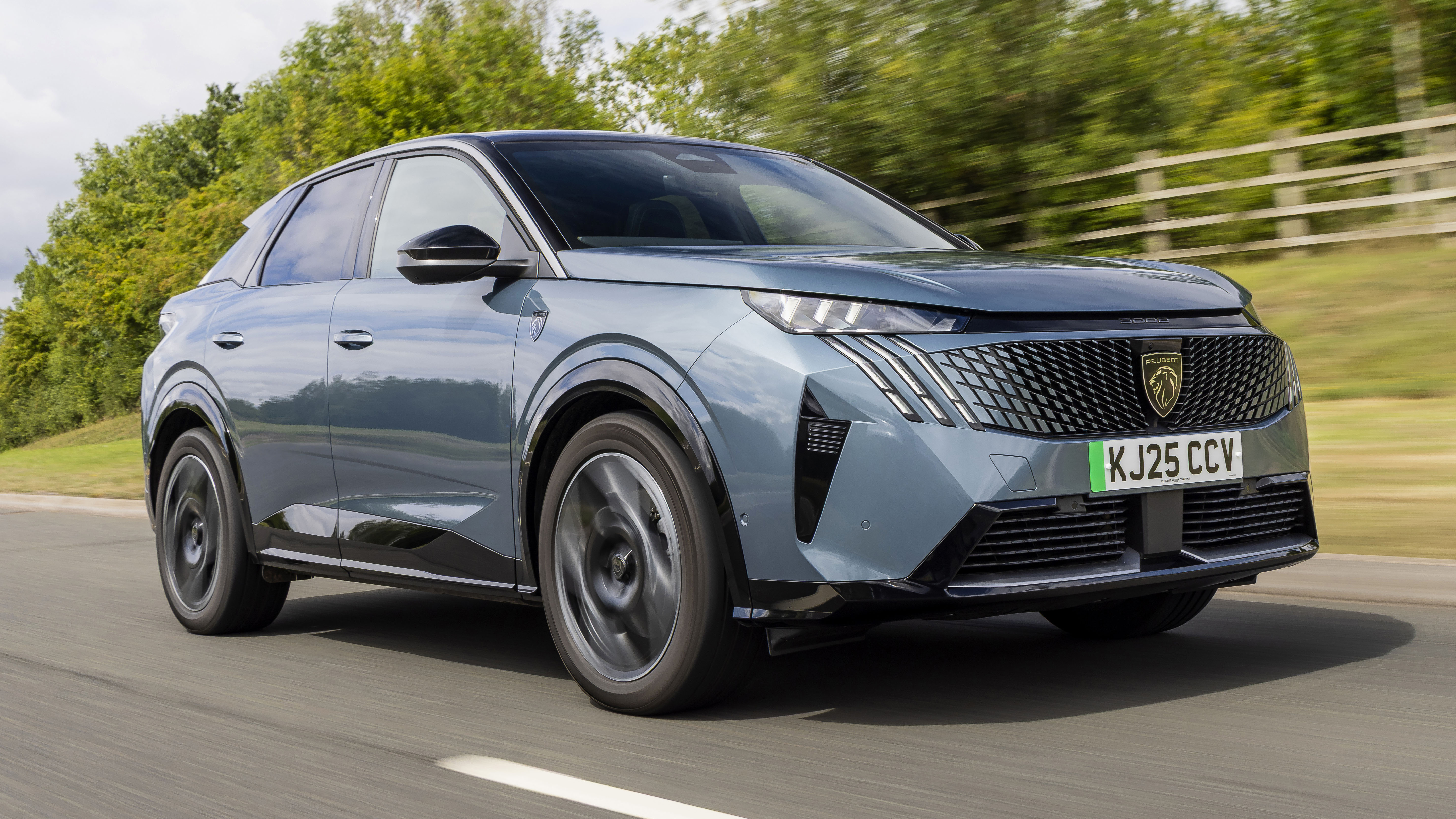 Image d'un SUV Peugeot E-3008 bleu foncé roulant sur une route de campagne.