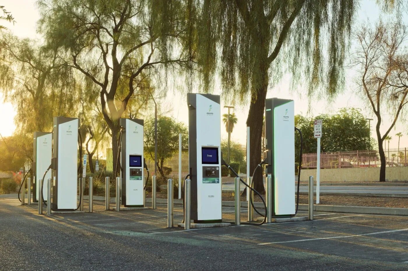 Un véhicule électrique de marque General Motors (GM) est connecté à une borne de recharge rapide Electrify America. La scène se déroule dans une station de recharge moderne, avec d'autres véhicules électriques en arrière-plan.