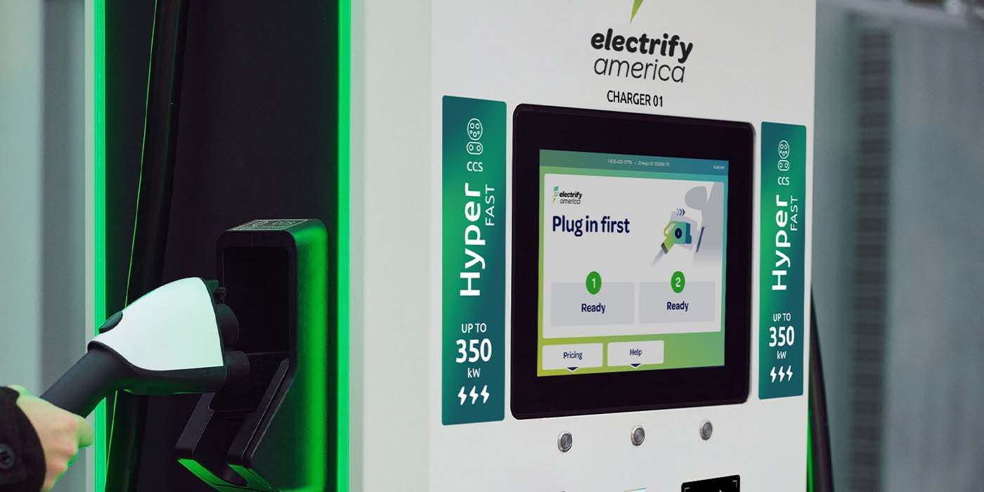 Une station de recharge Electrify America est présentée avec plusieurs bornes de recharge rapide de 350 kilowatts. L'infrastructure est moderne et prête à l'emploi.