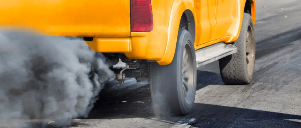 Un agent des impôts apposant un autocollant « Malus 2025 » sur le pare-brise d'une voiture compacte neuve dans un showroom.