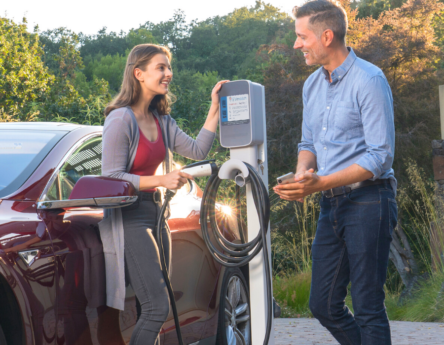 Une famille souriante devant une voiture électrique en charge à une borne publique, symbolisant l'attrait croissant pour l'électrification.