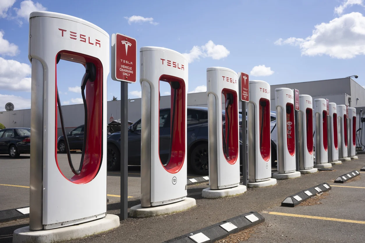 Plusieurs véhicules électriques de marques variées sont connectés à une station de recharge NACS, démontrant l'interopérabilité et la facilité d'utilisation du nouveau standard.